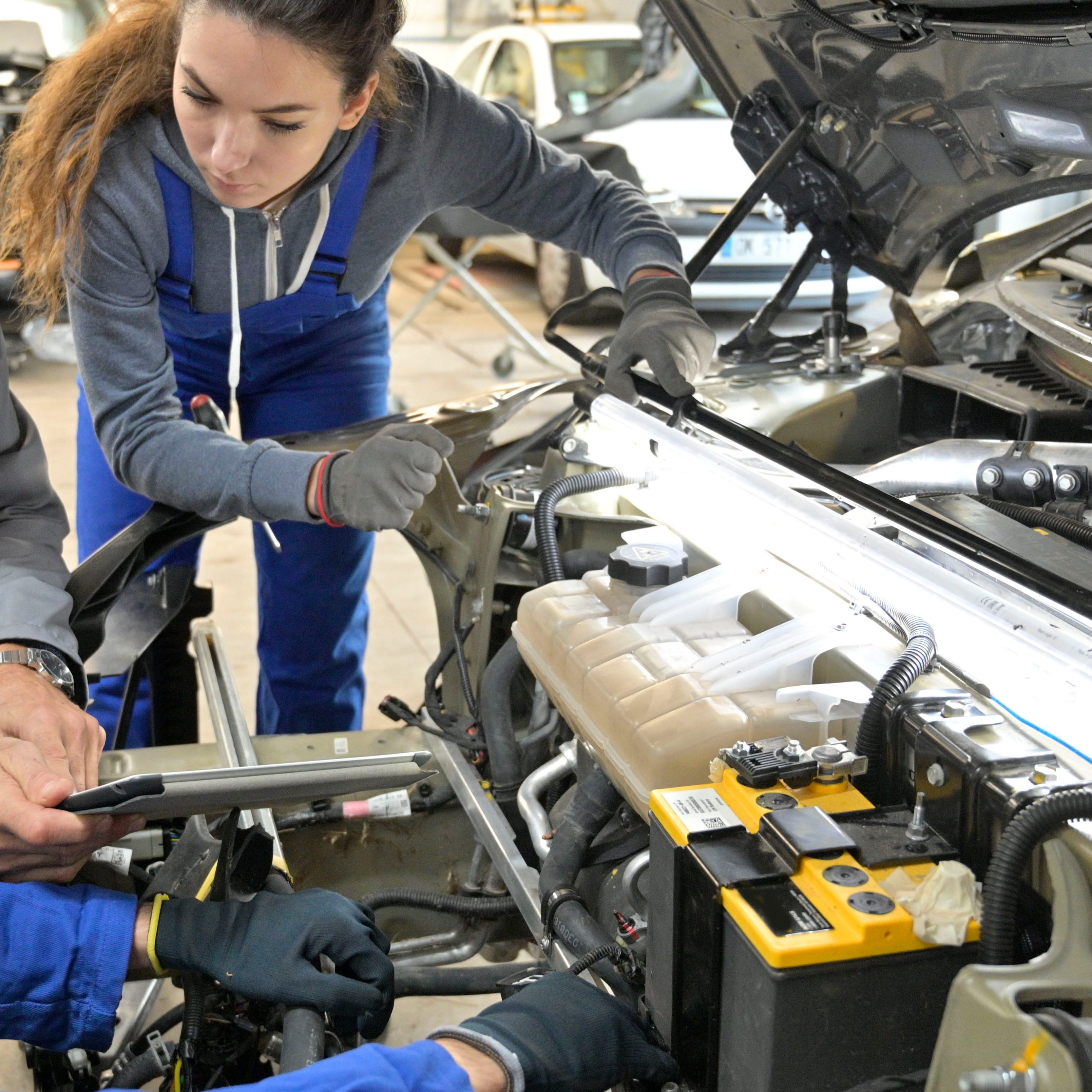 Instructor with trainees working on car engine